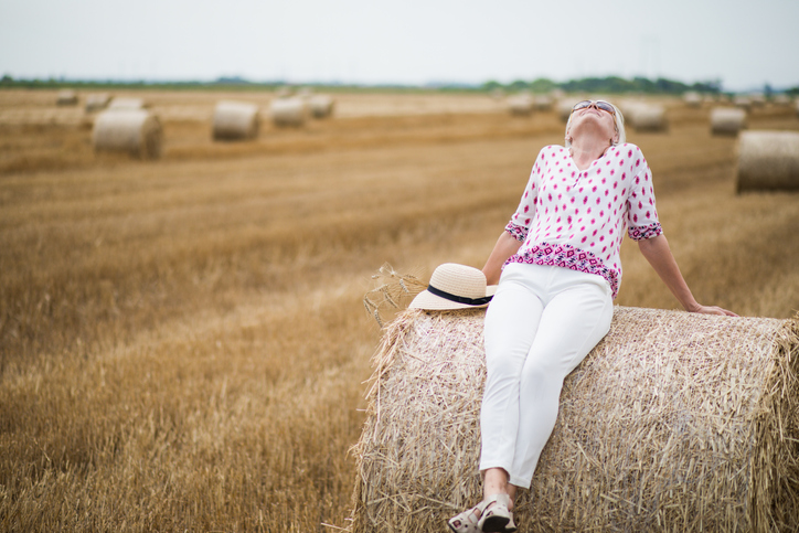 Happy attractive senior woman in a field in summer
